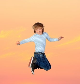 Adorable preteen boy jumping with a orange sky of background