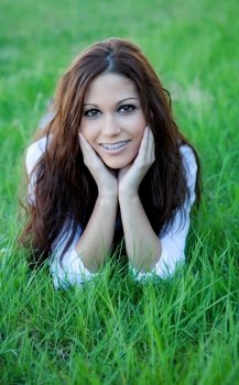Brunette cool girl with brackets lying on the grass