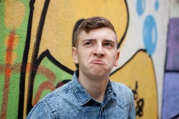 Pensive and funny teenager on a wall with graffiti background