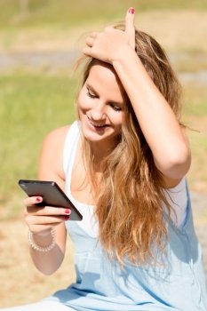 Pretty blonde girl on a sunny day field with a mobile