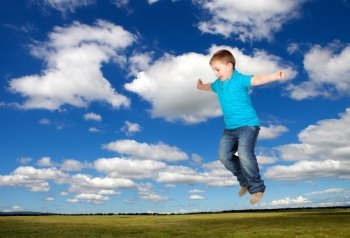 Happy child jumping on the medaw with a beautiful sky of background