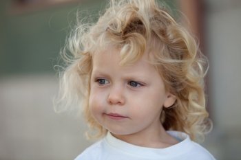 Beautiful boy three year old with long blond hair on a sunny day