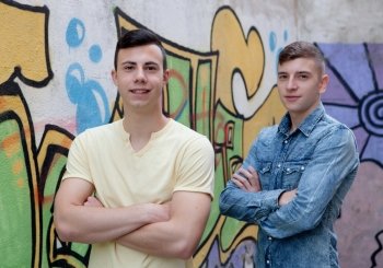 Two teenage boys in the street with graffiti background
