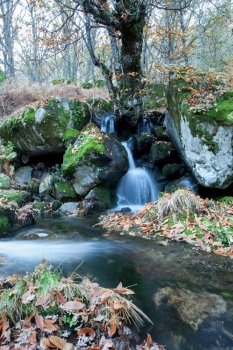 Beautiful waterfall and big rocks with moss in autumn