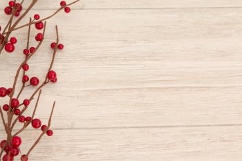 Christmas branch with red berries on a grey wooden background
