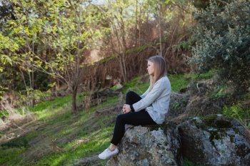 Young woman sitting on a big stone in a relaxed day