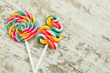 Colorful lollipops of different shapes on a wooden background