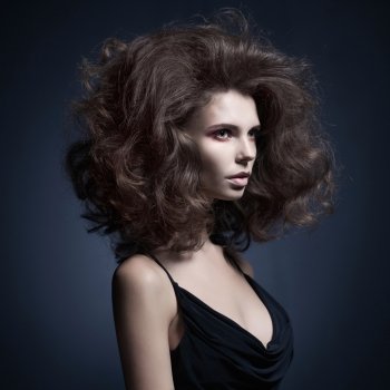 Studio fashion portrait of beautiful woman with volume wavy hair. Big hair