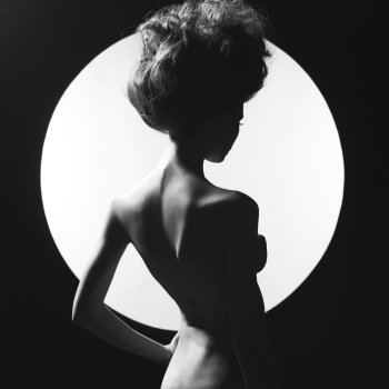 Black and white studio photo of nude elegant woman on geometric background