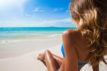 Woman sitting on beach. Woman in bikini sitting on the beach at sunny day