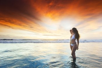 Woman in bikini at sunset. Beautiful sexy woman in bikini posing on beach at sunset