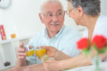 Elderly couple toasting with orange juice