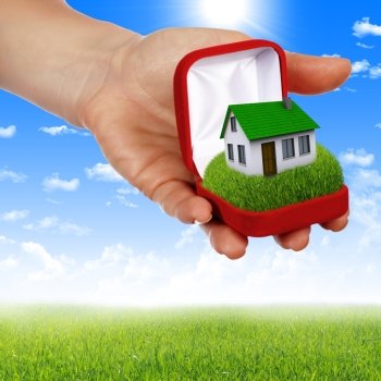 human hands holding model of a house against nature background