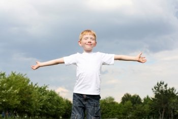 carefree litlle boy in the park embracing skies