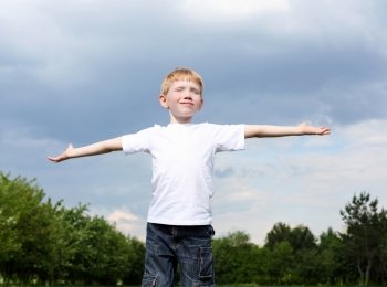 carefree litlle boy outdoors embracing skies on lawn