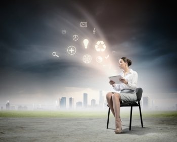 Email concept. Image of businesswoman sitting on chair with tablet pc in hands