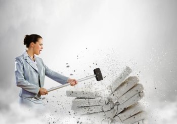 Physical strength. Image of businesswoman breaking bricks with hammer