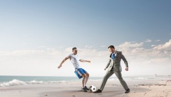 Businessman kicking ball. Young businessman in suit playing football at ocean coast