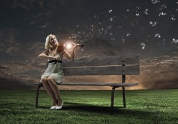 Girl with violin. Young woman sitting on bench and playing violin