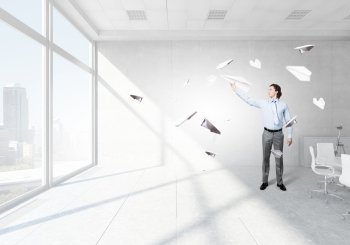 Young businessman in  modern office with paper plane in hand