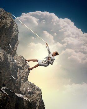 businesswoman climbing mountain. businesswoman climbing steep mountain hanging on rope
