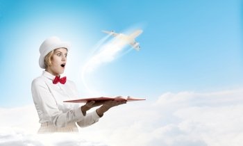 Astonished woman looking in book. Young woman in white hat with opened book in hands and airplane flying out
