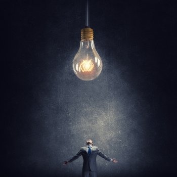 Big idea. Young businessman and glass glowing light bulb