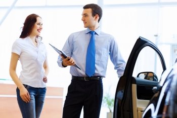 Young woman at car salon. Attractive woman at car salon with consultant choosing a car