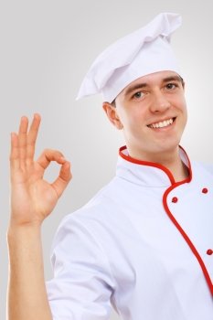 Portrait of a cook. Young male chef in red apron against grey background