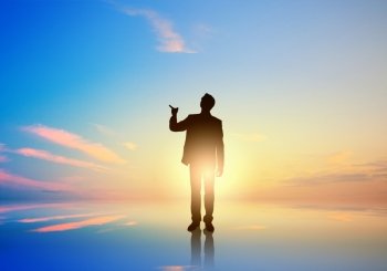 Silhouette of businessman standing with back on sunset background. Silhouette of businessman