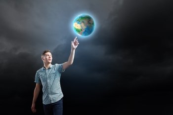 Ecology concept. Young man against dark background and Earth planet image. Elements of this image are furnished by NASA