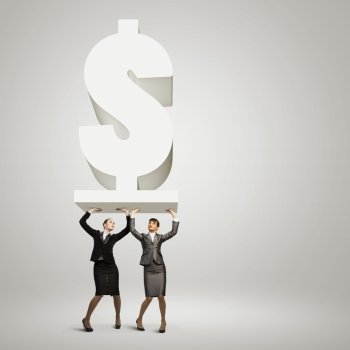 Money concept. Image of two businesswomen holding dollar sign above head