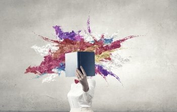 Book that blows up your mind. Woman with opened book against her face and colorful splashes coming from pages 