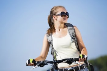 Young beautiful woman riding a bicycle in a park. Summer bike walk