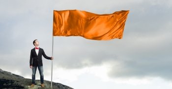 Guy with orange flag. Young man in bowtie with orange waving flag on stick