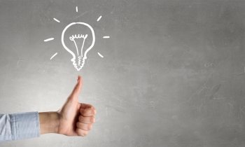 Bright idea in hand. Businessman hand showing thumb up and idea light bulb concept on concrete background