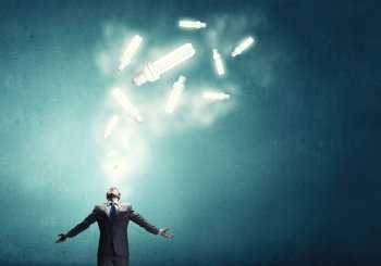 In light of success. Businessman with hands spread apart and light bulbs above