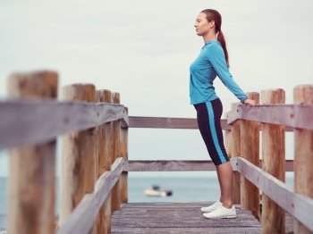 Sporty young woman stretching next to the sea coast