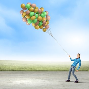 Woman with balloons. Young woman in casual holding bunch of colorful balloons