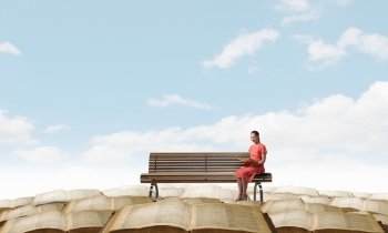 Read to broaden your mind. Young attractive woman sitting on bench and reading book