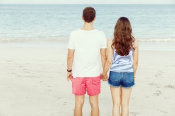 Romantic young couple standing on the beach. Romantic young couple standing on the beach looking at the ocean