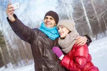 Selfie in park. Happy young couple in winter park having fun
