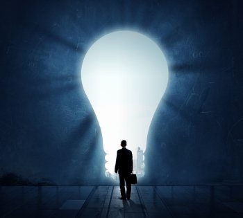 Great bright idea for success. Back view of businessman standing in light of idea concept