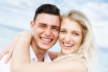 Romantic young couple sitting on the beach. Romantic young couple sitting on the beach looking at camera