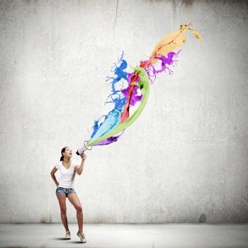 Girl with megaphone. Young woman in casual speaking in megaphone with colorful splashes flying out