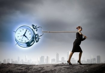 Time is money. image of businesswoman pulling alarm clock with rope