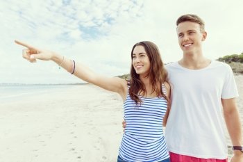 Happy young man and woman couple together walking on a beach. Happy senior man and woman couple together walking and pointing on a deserted beach