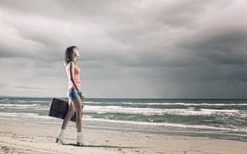 Summer traveling. Young woman tourist walking with suitcase at seaside