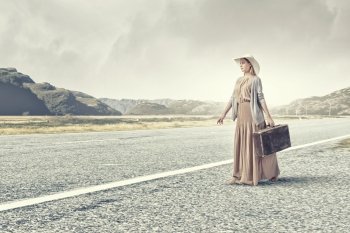 Woman with old suitcase. Beautiful woman with retro suitcase walking on road 