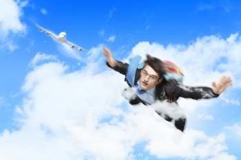 Young businessman flying with parachute on back. Conceptual image of young businessman flying with parachute on back